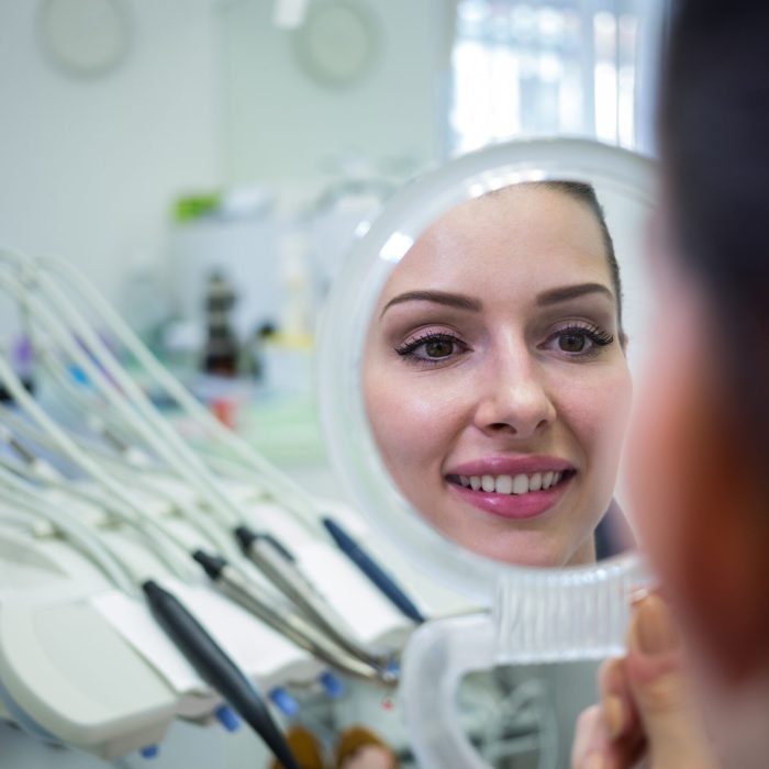 Patient looking at her face in mirror at clinic Patient looking at her face in mirror at clinic